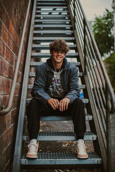 a young man sitting on top of a set of stairs next to a brick wall