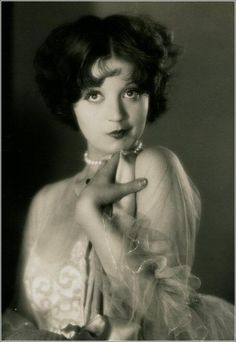 an old black and white photo of a woman with her hand on her chin, posing for the camera