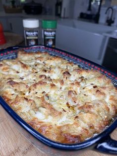 a blue casserole dish filled with food on top of a wooden table in a kitchen