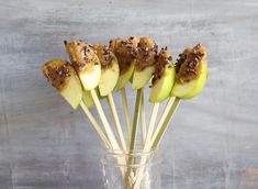 a glass vase filled with apples covered in chocolate chips and sprinkled with nuts