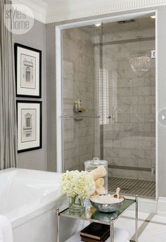 a white bath tub sitting next to a walk in shower under a chandelier