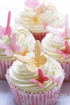 cupcakes with white frosting and pink butterflies on the top one is decorated