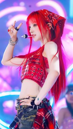 a woman with red hair and piercings holding a microphone in her right hand while standing on stage