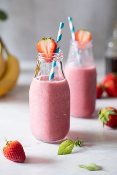 two mason jars filled with smoothies and strawberries