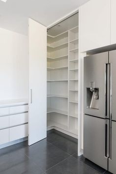 a refrigerator freezer sitting inside of a kitchen next to white cupboards and drawers