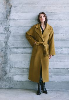 Introducing our loose-fitting mustard-colored wrap wool coat, designed for both lightness and comfort. The H-shaped silhouette offers versatility and suits different body types, ensuring a flattering look. With two practical patch pockets, this coat effortlessly combines functionality and style, allowing you to keep your essentials within easy reach. The lowered shoulders add a relaxed and contemporary touch. The belt accentuates the waist, creating an attractive and feminine silhouette. Crafted Yellow Wool Outerwear For Winter, Chic Yellow Oversized Outerwear, Chic Mustard Outerwear For Work, Chic Oversized Yellow Outerwear, Chic Mustard Outerwear For Fall, Mustard Coat, Fall Wraps, Oversized Wool Coat, Navy Blue Coat