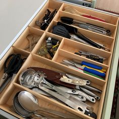 an open drawer with utensils and spoons in it on top of a counter