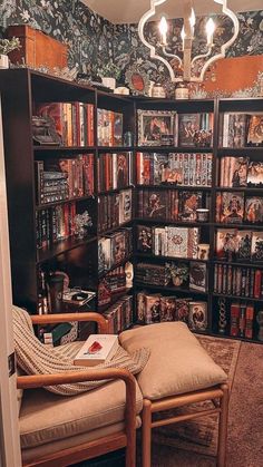 a room filled with lots of books and furniture next to a chandelier hanging from the ceiling