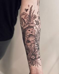 a person's arm with flowers and an owl in the center on top of it