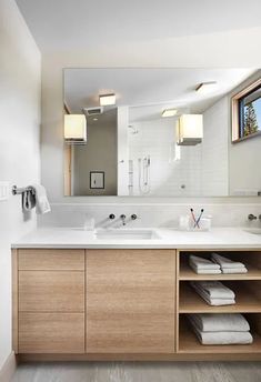 a bathroom with two sinks, mirrors and towels on the shelf in front of it