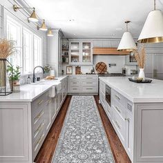 a large kitchen with white cabinets and wooden floors, along with an area rug on the floor