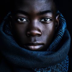 a man with blue eyes and a scarf around his neck is staring into the camera