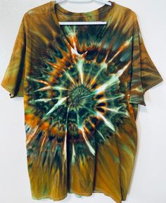 a tie - dyed shirt hanging up on a hanger in front of a white wall