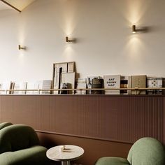 two green chairs sitting next to each other in front of a wall with pictures on it