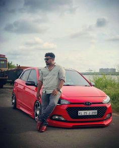 a man sitting on the hood of a red car