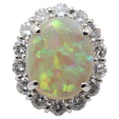 A fine and natural Australian opal takes center stage of this lovely platinum made ring. The opal weighs 3.59 carats and has excellent play-of-color as large bright flashes of green, blue, yellow, and orange can be seen on the stone. Its strong play-of-color makes us believe it comes from the Lighting Ridge area of Australia. It is accented by 1.30 carats of large round brilliant-cut diamonds which adds sparkle and brilliance to the ring. Hand-fabricated in platinum and ready to be worn. Ring Si Platinum Ring, Australian Opal, Round Brilliant Cut Diamond, Cocktail Rings, Halo Diamond, Halo, Platinum, Gemstone Rings, Opal