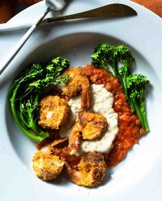 a white plate topped with shrimp and broccoli next to a fork on a table