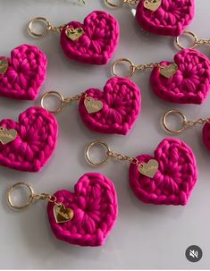 pink crocheted heart keychains with gold hearts on them are arranged in a row