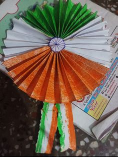 an orange and white paper fan sitting on top of a table