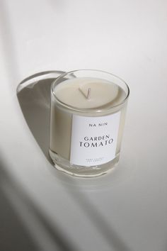 a candle that is sitting on a table next to a white wall with the words carpia tomatio written in it