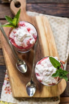 two glasses filled with ice cream on top of a wooden cutting board