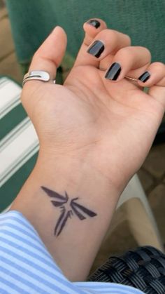 a woman's wrist with a small tattoo on her left hand and a bird on it