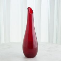 a red vase sitting on top of a white table