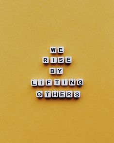 the words we rise by lufting others are spelled in small cubes on a yellow background