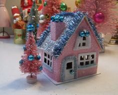 there is a small pink house with blue ornaments on it and trees in the background