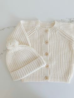 Unlock a world of warmth and comfort with this cozy Chunky Knit Cardigan! Perfect for a chilly day, it'll keep your little one snug and stylish with its traditional knit design, front buttons for convenience, and snug fit. Wrap your little one in chunky knit cuteness! Pair this cardigan with our 'Chunky Knit Beanie' Cozy Winter Sweater For Playtime, Cream Soft Knit Cotton Outerwear, Cream Cotton Cardigan With Soft Knit, Cream Cotton Outerwear With Soft Knit, Soft Knit Sweater For Playtime In Fall, White Winter Cardigan For Playtime, White Cardigan For Winter Playtime, Winter Cotton Cardigan For Playtime, Winter Playtime Cotton Cardigan