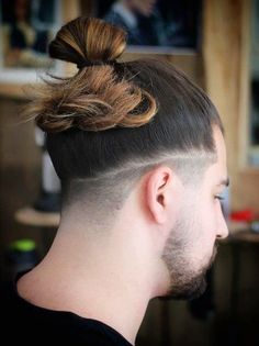 a man with a top knot undercut and a bun in his hair is seen from the side