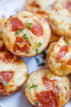 mini pizzas with cheese and pepperoni are on a white plate, ready to be eaten