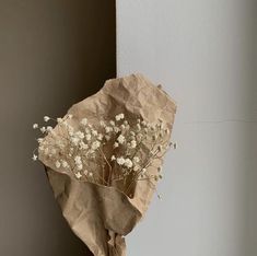 a bouquet of dried flowers sitting on top of a piece of brown paper next to a wall