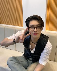 a young man sitting on top of a white couch holding his hand up to the side