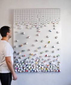 a man standing in front of a white wall with many pieces of paper on it