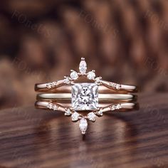 an engagement ring with a princess cut diamond in the center on top of a wooden table