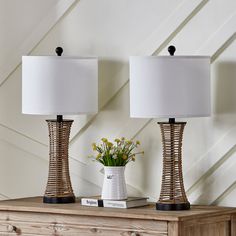 two lamps sitting on top of a dresser next to a vase with flowers in it