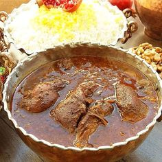 a large metal bowl filled with food on top of a wooden table next to other foods