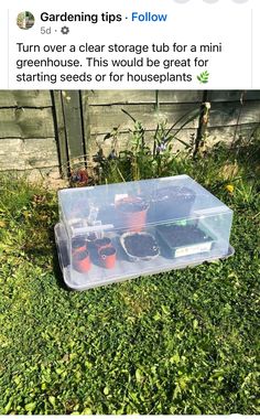 a plastic container filled with plants sitting in the grass