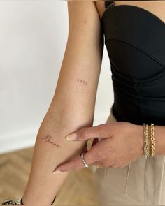 a woman's arm with the word love tattooed on her left arm and two gold bracelets