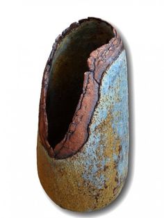 an old, rusted vase is sitting on a white surface with a hole in the middle