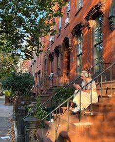 a woman is sitting on the steps in front of an apartment building