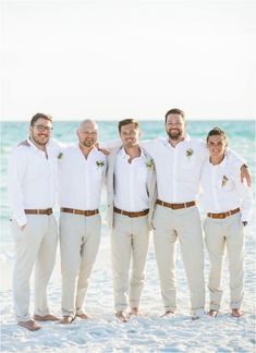 a group of men standing next to each other on top of a sand covered beach