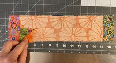 someone is cutting up some fabric on a ruler and measuring it for the pattern to be sewn