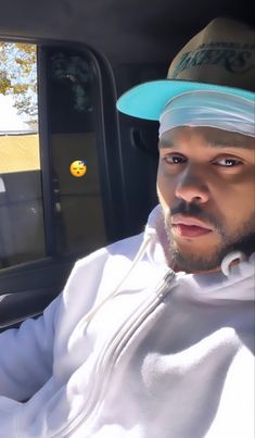 a man wearing a hat sitting in the passenger seat of a car with his eyes closed