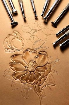 some metal tools are laying on top of a piece of paper with flowers drawn on it