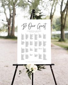 a wedding seating sign with flowers and greenery on the top is shown in front of some trees