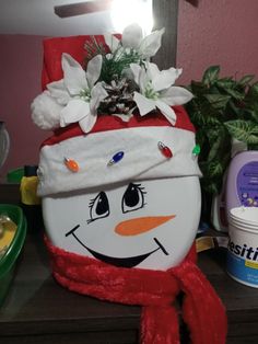 a snowman toilet seat cover sitting on top of a wooden table next to a potted plant