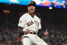 a baseball player is laughing while standing in the outfield at a game with his mouth open