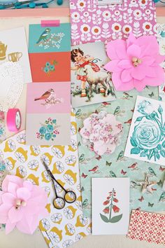 many different types of paper and flowers on the table with scissors, cards, and other items